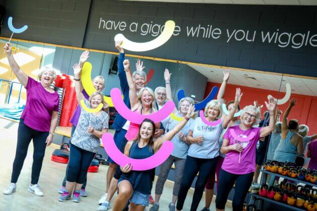 Group of women gym members smiling and waving
