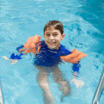 boy wearing a rash vest and water wings in the pool