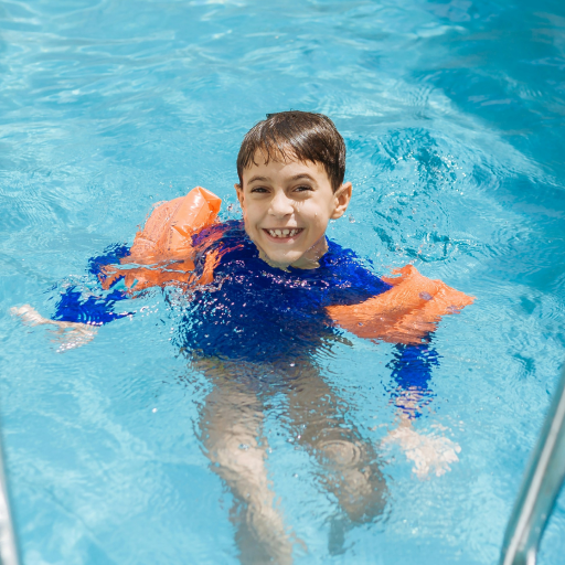 boy wearing a rash vest and water wings in the pool